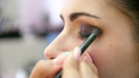 Hands make-up artist applied makeup on the face of a young woman. Girl doing eye Vidéo 107182897
