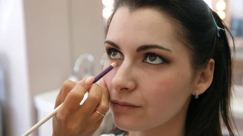Hands make-up artist applied makeup on the face of a young woman. Girl doing eye Stock Footage 107278224