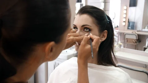 Hands make-up artist applied makeup on the face of a young woman. Girl doing eye Stock Footage 107279231