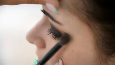 Hands make-up artist applied makeup on the face of a young woman. Girl doing eye Stock Footage 107279400