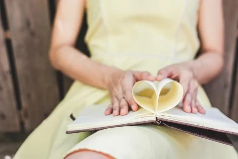 Hands make a book paper shape heart. Love concept. Stock Photos