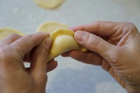 Hands make dumpling by folding dough on flat surface in kitchen during daytim Stock Photos
