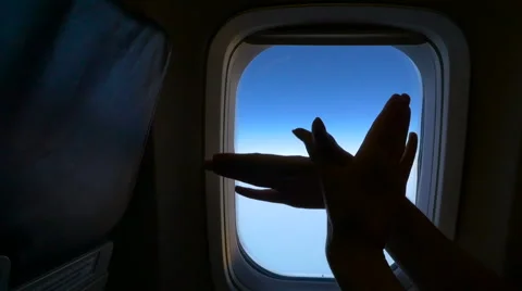 Hands make gesture of soaring birds on the background of the airplane window. HD Stock Footage 67184486