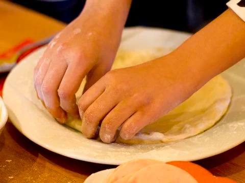 Hands make pizza, work with dough on a white plate Stock Photos