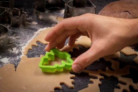 Hands making biscuits using cookie cutter to cut out flat pastry dough closeup Foto stock