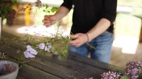 Hands making bouquet from summer wild flowers close up at wooden rustic table  Stock Footage 89872995
