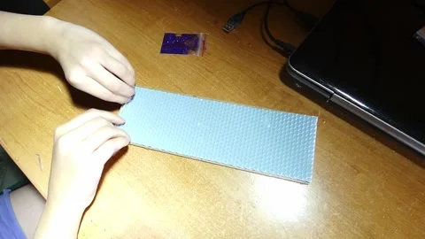 Hands making a creative project with blue material and tools on a desk Stock Footage 328416198