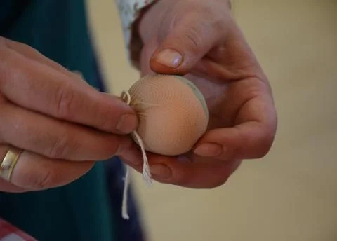 Hands making Easter egg decoration with fabric and thread craft process Stock Photos