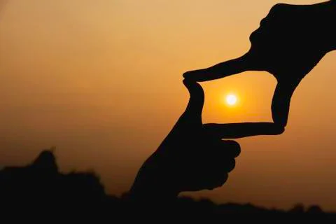 Hands making frame with sunset. Close up of woman hands making frame gesture. Stock Photos