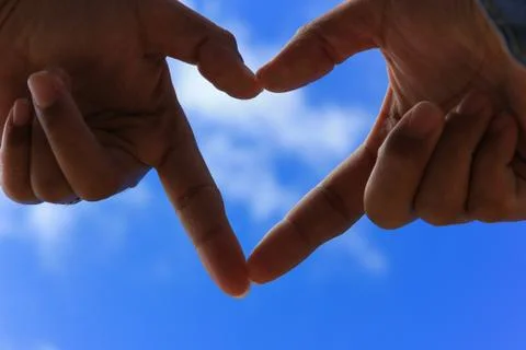 Hands making a heart shape with blur blue sky. Love and Valentine day concept Stock Photos