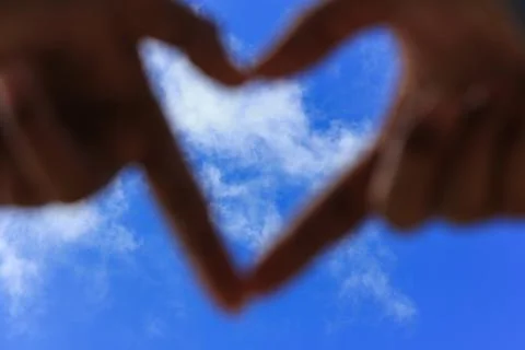 Hands making a heart shape with blur blue sky. Love concept Stock Photos