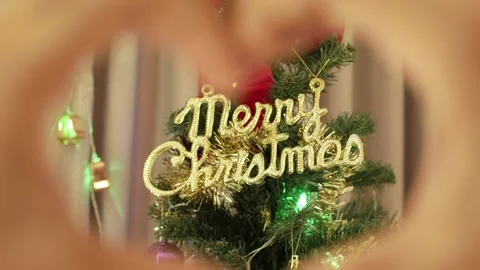 Hands making heart symbol in front of a Christmas tree Stock Footage 239020266