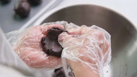 Hands making homemade cocoa balls stuffed with dark chocolate cubes at home. Видео 177442258