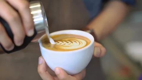 Hands making latte art at a cafe. Making Latte Art by pouring milk into coffee. Stock-Footage 334648529