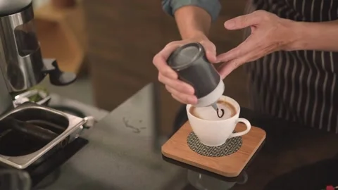 Hands making latte art at a cafe. Making Latte Art by pouring milk into coffee. 動画素材 334649911