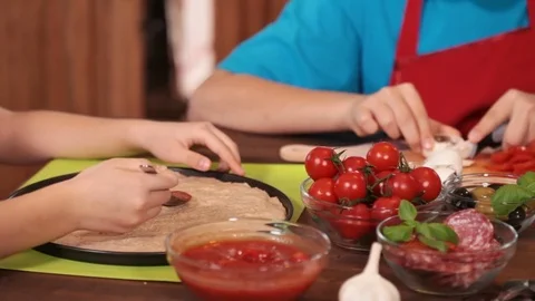 Hands making a pizza spreading the sauce, and preparing ingredients - closeup Stock Footage 80252394