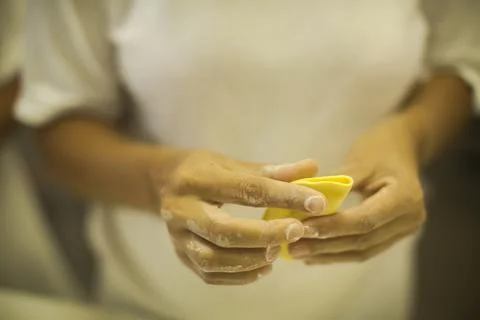 Hands making Raw and dry capeletti pasta on kitchen table Stock Photos