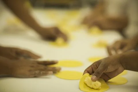 Hands making Raw and dry capeletti pasta on kitchen table Stock Photos