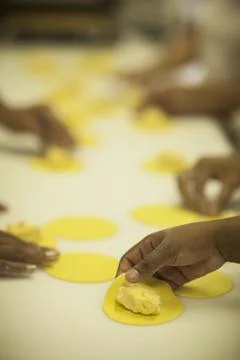 Hands making Raw and dry capeletti pasta on kitchen table Stock Photos