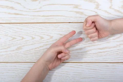 Hands making rock, paper, scissors gesture on wooden background Stock Photos