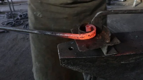 Hands of a male blacksmith bends a red-hot iron into a spiral shape  slow motion Stock Footage 120112734