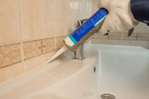 Hands of male plumber fixing a sink in bathroom Stock Photos