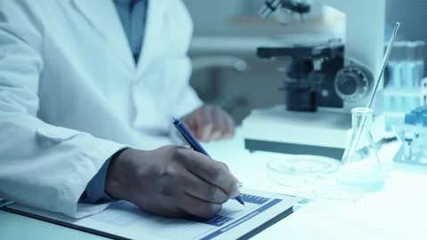Hands of Male Scientist Working with Microscope and Taking Notes at Desk in Lab Stock Footage 275495639