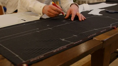 Hands of male tailor drawing pattern in studio. man's hand draws with chalk Stock Footage 127217952