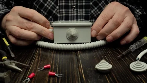 Hands of a male technician assembling a wiring box with flexible conduit and Stock Footage 335320082