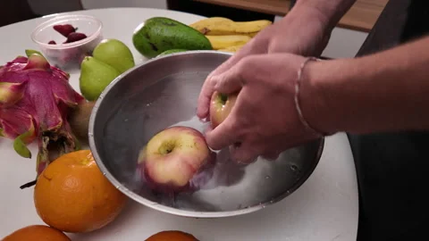 Hands of a man in an apron standing in front of a table with various fruits and Stock Footage 318345855
