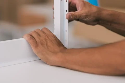 Hands of a man assembling two pieces of furniture in a workshop Stock Photos