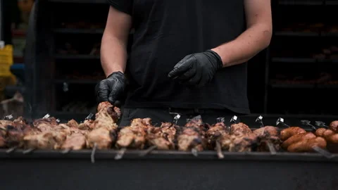 Hands of a man in black gloves rotating a barbecue on the fire Stock Footage 186010095