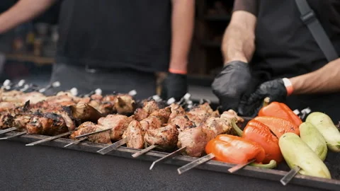 Hands of a man in black gloves rotating a barbecue on the fire Stock Footage 186010768