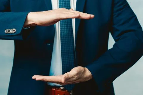 Hands of a man in a blue jacket folded in the shape of a sphere or as if pull Stock Photos
