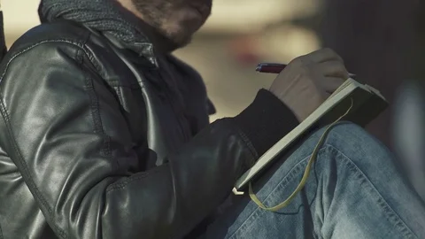 Hands of man busily writing on a notebook under a tree Video stock 71891760