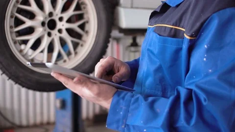 Hands of man car mechanic with tablet with lifted car on background Stock Footage 74902371