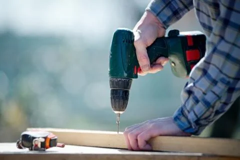 Hands of a man carpenter builder working with a electric screwdriver Stock Photos