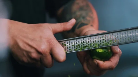 Hands man chef rubbing a lime peel on a grater in a restaurant kitchen cut fruit Stock Footage 100303105
