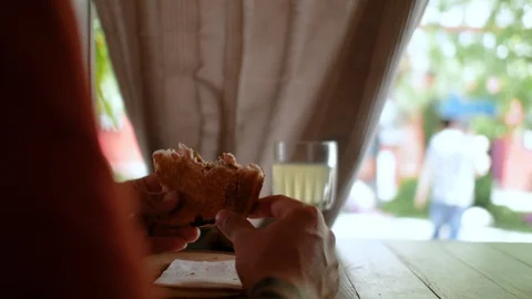 Hands of a man close up holding a sandwich in a cafe near the street. 4k. 4k Stock Footage 109692126