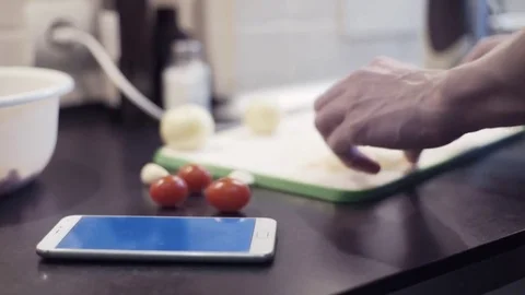 Hands man cutting onion at kitchen preparing vegetable food and using smartphone Stock Footage 74163859