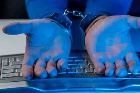 Hands of a man in handcuffs on a background of a computer keyboard Stock-Fotos