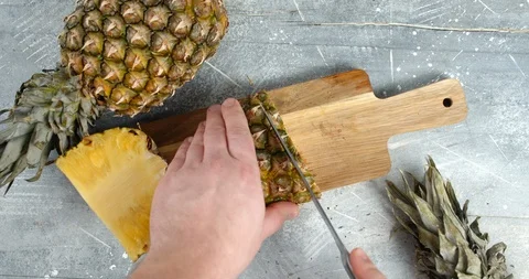 Hands man with knife cut the pineapple on cutting Board. 스톡 동영상 129801112
