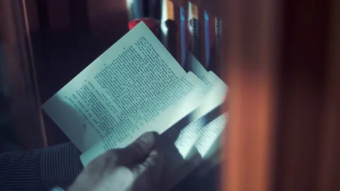 Hands of a man leafing through a book on the background many rows of books Stock Footage 121088275