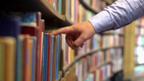 The hands of a man in a library picking out and reading a book Video stock 80076511