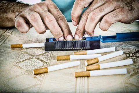 Hands of man making cigarettes Stock Photos