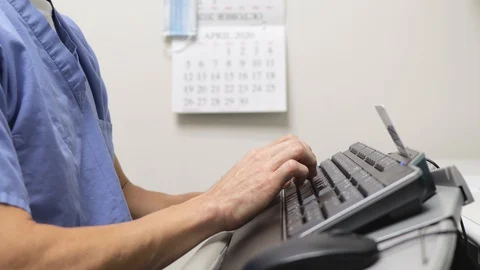 Hands of man male nurse doctor typing on keyboard computer, charting data. Stock Footage