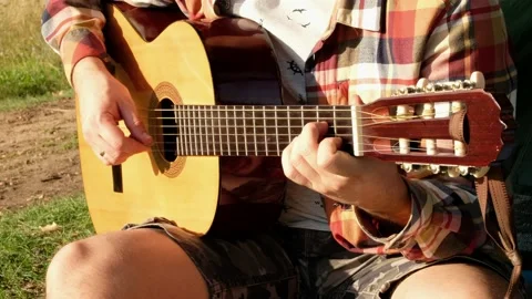 Hands of man that is playing at the guitar during the summer picnic on nature. Stock Footage 138936107
