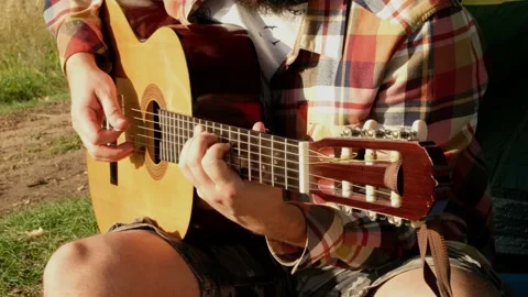 Hands of man that is playing at the guitar during the summer picnic on nature. Stock Footage 139921209