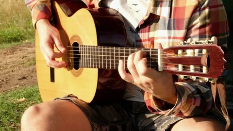 Hands of man that is playing at the guitar during the summer picnic on nature. Stock Footage 141258702