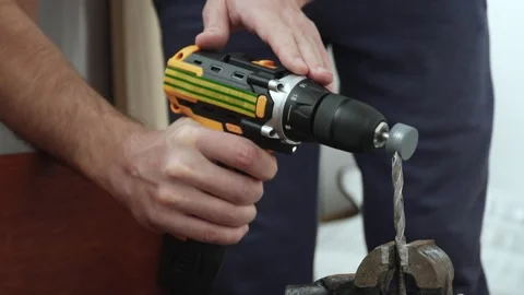 Hands of man with power drill sharpening drill bit in vise using grinding stone. Stock Footage 334339152